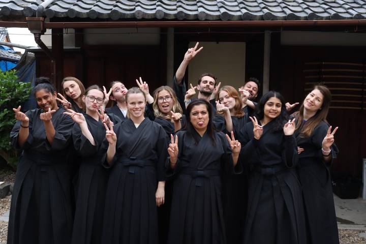 Group dressed in black martial-arts robes making playful peace signs for the camera.