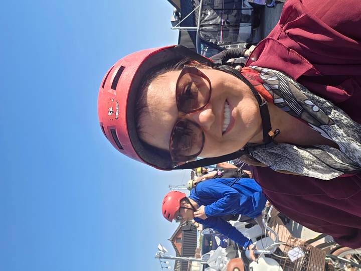 Woman taking a helmeted selfie under a clear blue sky during an outdoor tour.