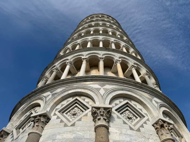 Dramatic worm's-eye view of the Leaning Tower of Pisa against a deep blue sky.