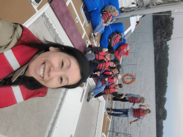 Traveler takes selfie with friends in red lifejackets relaxing on catamaran at sea.