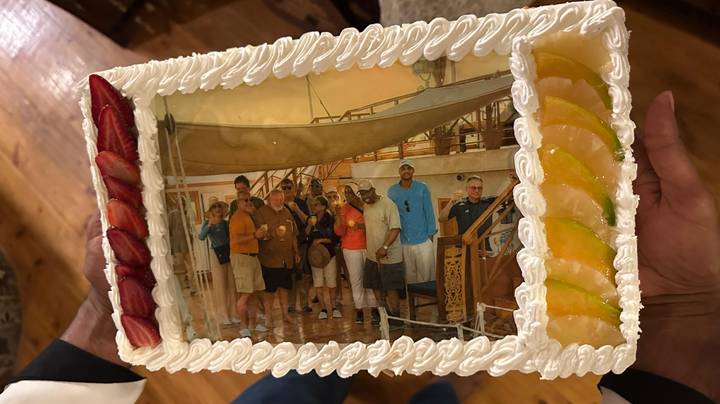 Decorative cake featuring a printed photo of a tour group on board a river cruise ship.