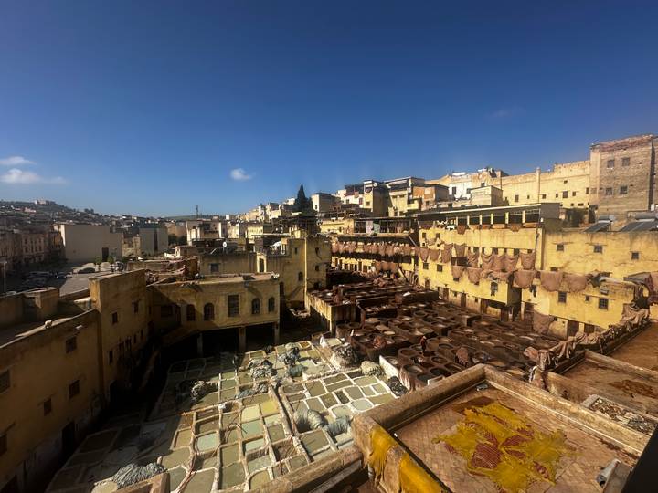 Panoramic view over Fes’s famous leather tanneries with rows of stone vats under blue skies.