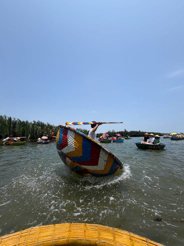 Colorful round basket boats and paddlers enjoying a sunny day on a calm river inlet.