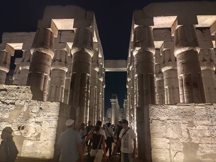 Night visit to Luxor Temple’s grand colonnade lit dramatically with tourists walking between the pillars.