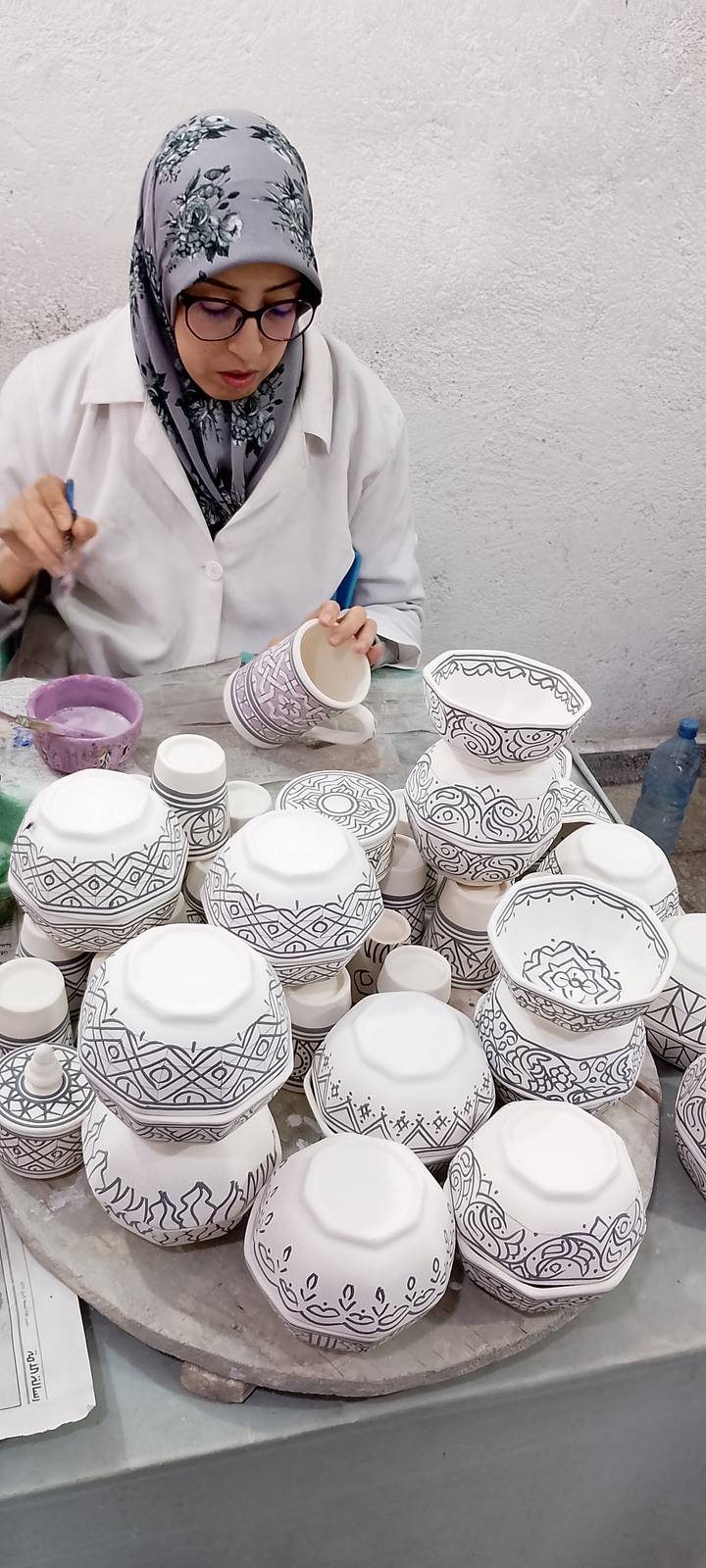 Artisan painting intricate geometric designs on ceramic bowls