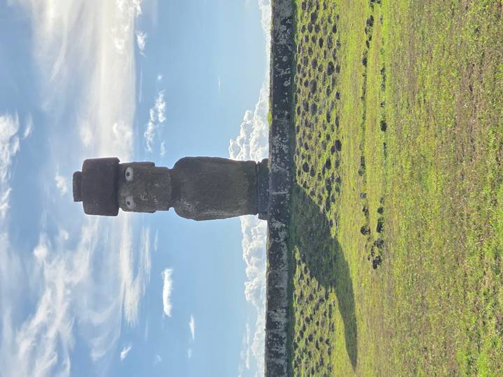 Single Moai with pukao topknot standing on stone platform under partly cloudy sky