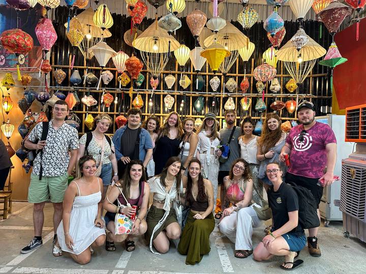 Large group stands inside lantern showroom surrounded by hanging silk lights.