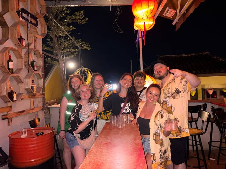 Small group enjoying rooftop bar at night with lantern decor.