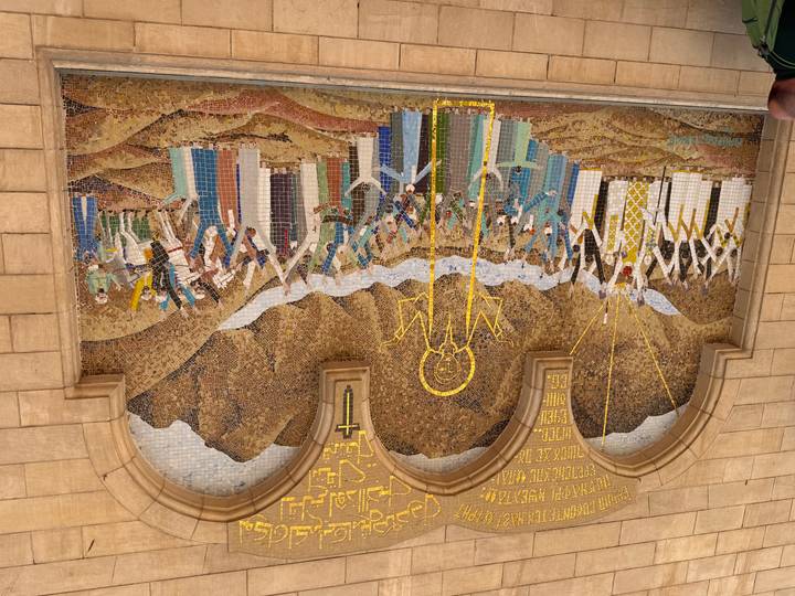 Large colorful mosaic mural depicting a biblical scene on a stone church wall.