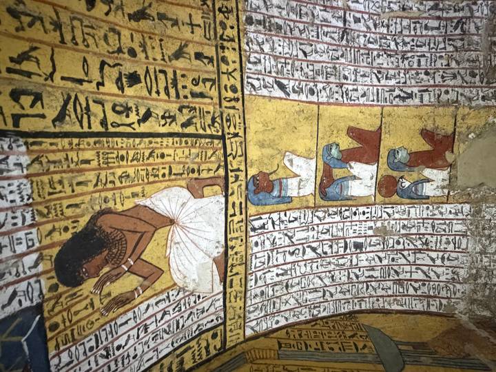 Colorful frescoes and hieroglyphs depicting ancient Egyptian figures line the curved walls of a tomb chamber.