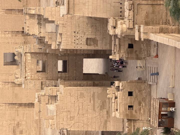 Group of tourists stands in a narrow temple doorway seen from above through multiple stone portals.