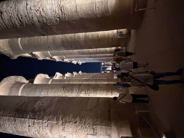 Nighttime walk through a colonnaded avenue of Luxor Temple illuminated by warm lights.