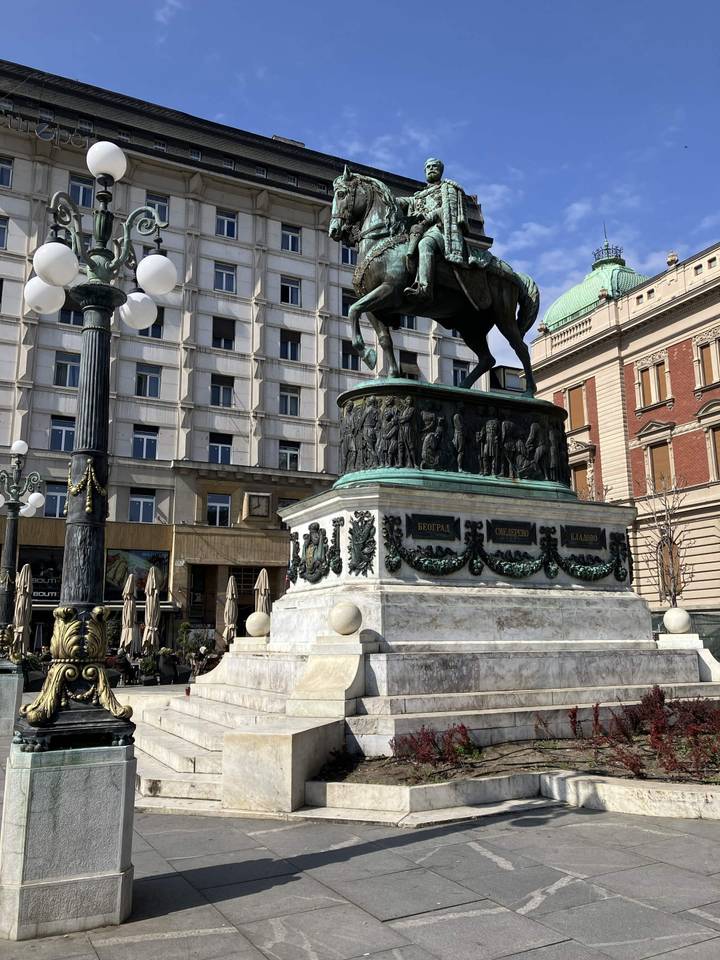 Equestrian statue of a prince dominates city square backed by classic European facades.