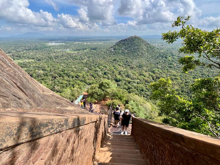 Steep stone stairway on Sigiriya rock offers sweeping views over jungle plain.