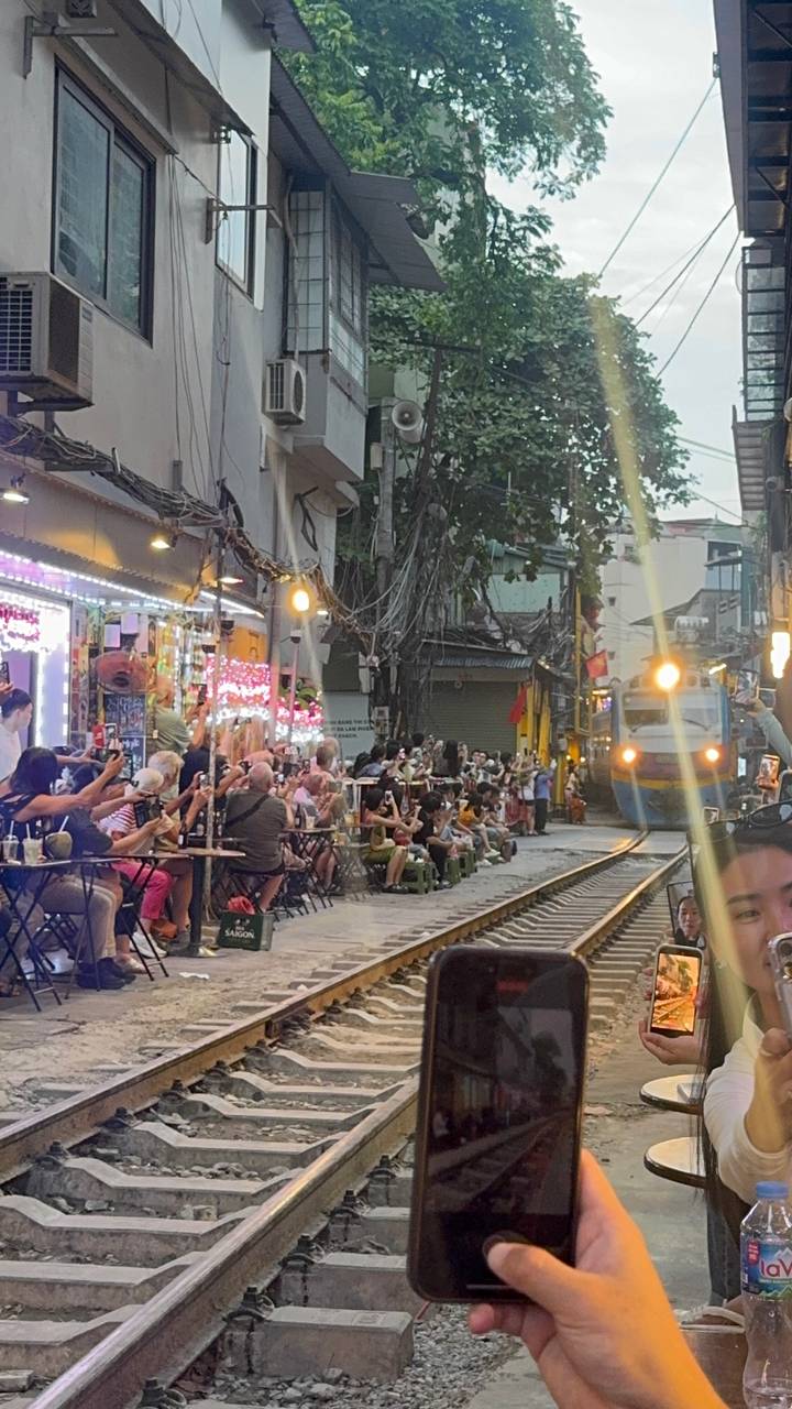 Crowds seated at café tables mere inches from railway tracks as a train passes through Hanoi’s famous Train Street.
