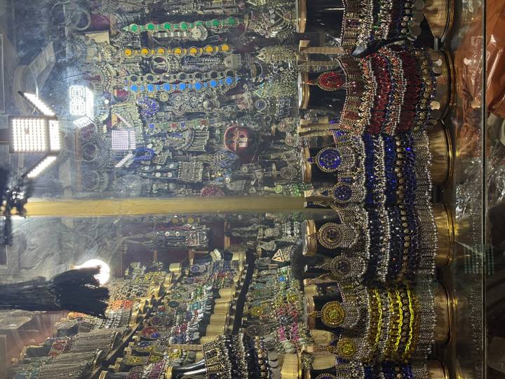 Colorful display of traditional Pakistani jewelry and trinkets sparkling under bright shop lights.
