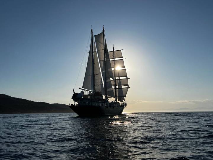 Silhouetted sailing vessel backlit by the low sun creating a dramatic seascape