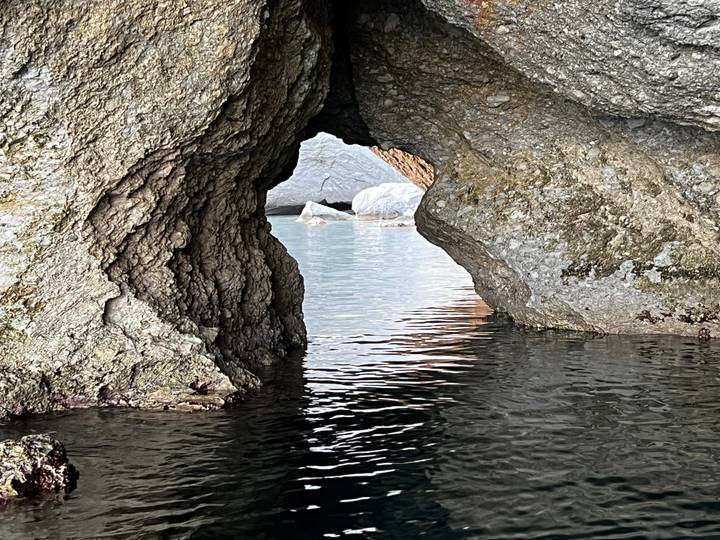 Close interior view of a small sea cave opening onto tranquil water