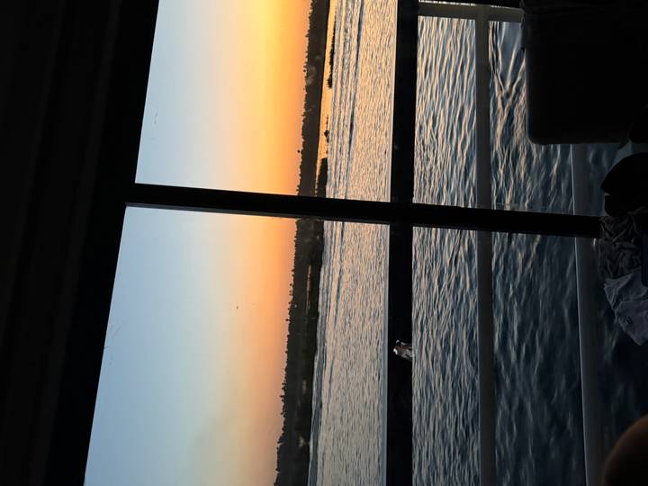 View through a cabin window of the Nile at dusk, with soft orange and blue twilight over the river.