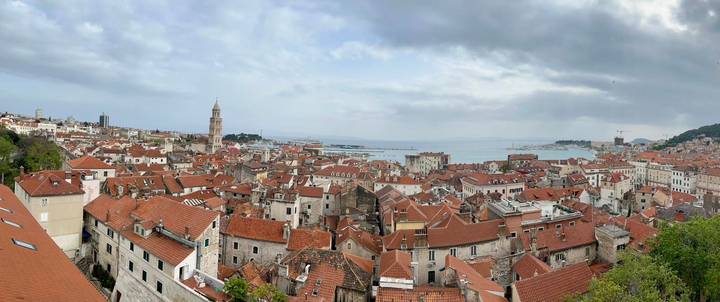Panoramic skyline of Split, Croatia with red-tiled roofs, cathedral bell tower and Adriatic Sea beyond.