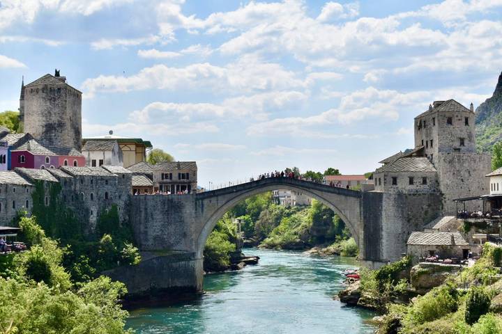 The iconic Stari Most stone bridge arches over a turquoise river framed by medieval towers.