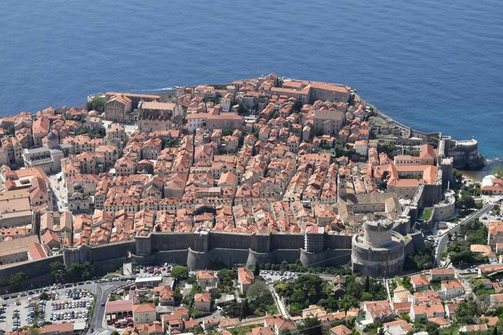 Spectacular aerial view of Dubrovnik’s walled old town jutting into the vivid blue Adriatic Sea.