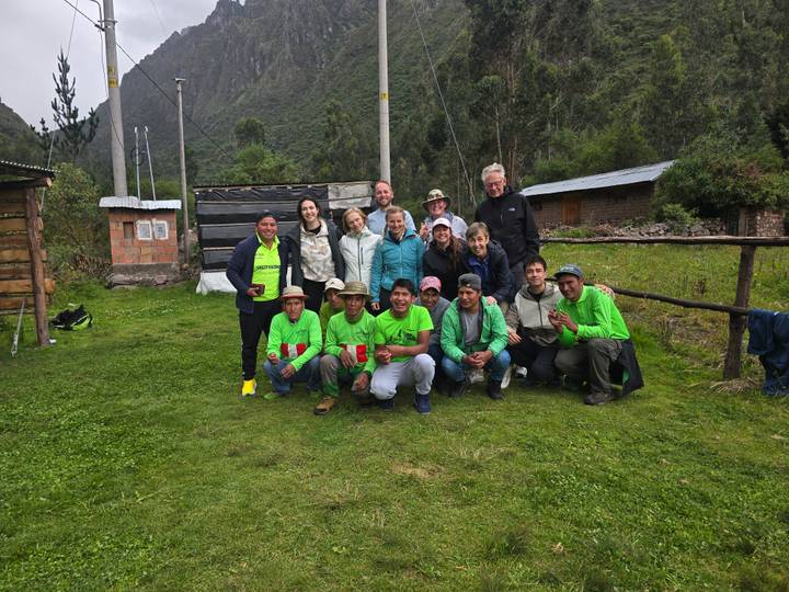 Trekkers and local crew pose together on a grassy clearing in the Andes after the hike.