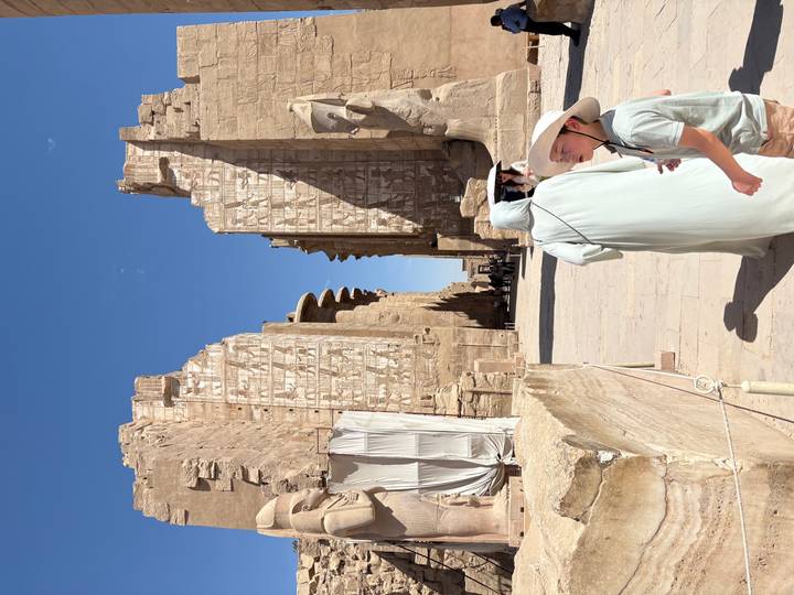 Visitors walk through the monumental entrance lined with colossal statues at Karnak Temple.