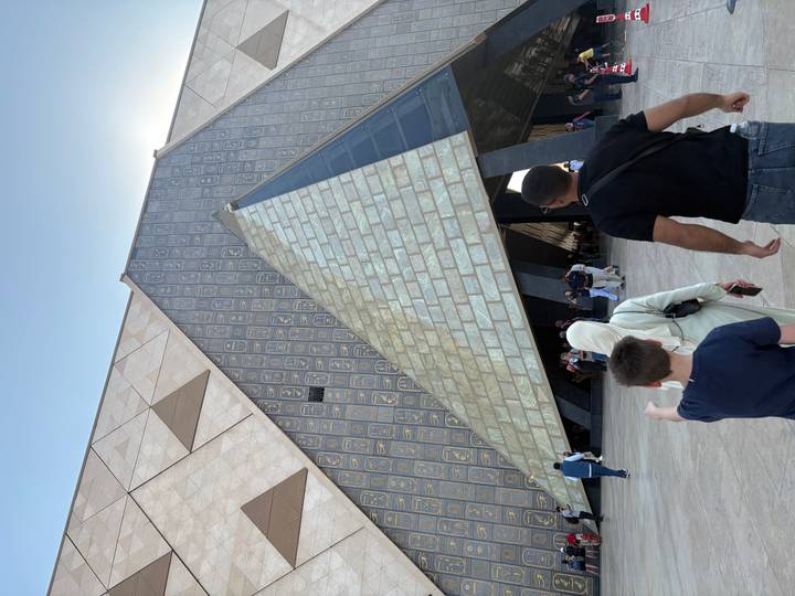 Family approaches the angular glass and stone facade of the Grand Egyptian Museum in Giza.