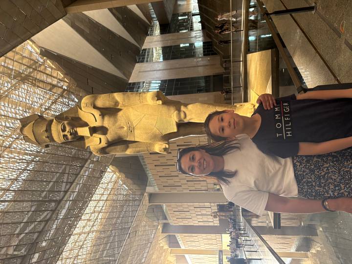 Mother and son stand before the towering statue of Ramses II inside the Grand Egyptian Museum.