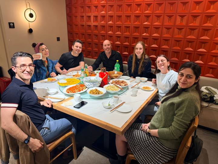 Friends share a table filled with Chinese dishes inside a modern restaurant.