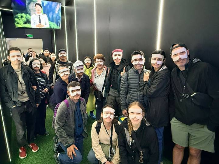 Indoor group wearing playful paper masks posing under strip lighting.