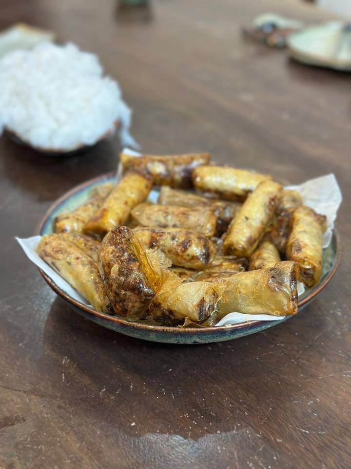 Plate piled high with freshly fried Vietnamese spring rolls on parchment paper.