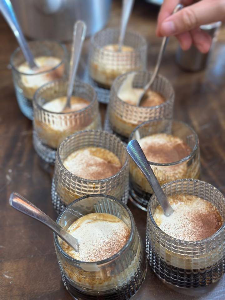 Close-up of several glass cups filled with a creamy dessert topped with cinnamon.
