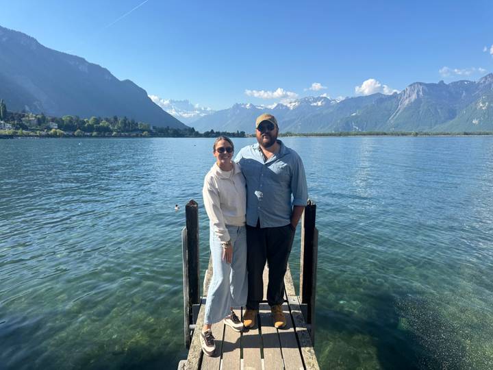 Couple standing on a narrow wooden jetty over the crystal waters of a mountain lake.