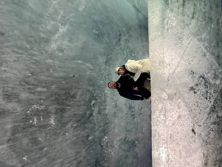 Couple inside an icy cavern surrounded by shimmering blue glacial walls.
