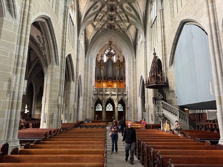 Grand gothic cathedral interior with soaring arches and ornate pipe organ above the nave.
