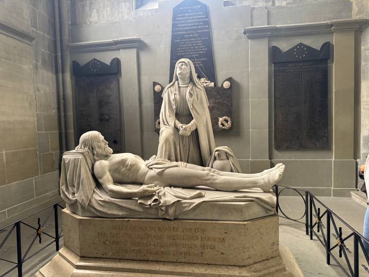 Marble sculpture of a recumbent figure with mourning woman in a historic church alcove.
