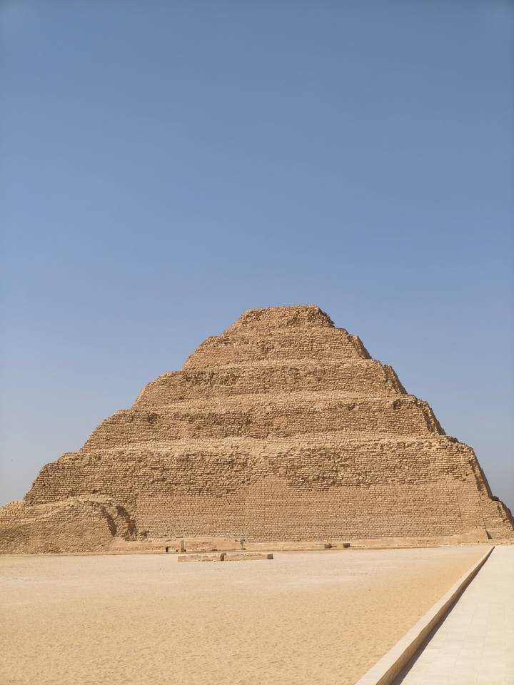 The Step Pyramid of Djoser rises in layered limestone tiers against a cloudless sky.