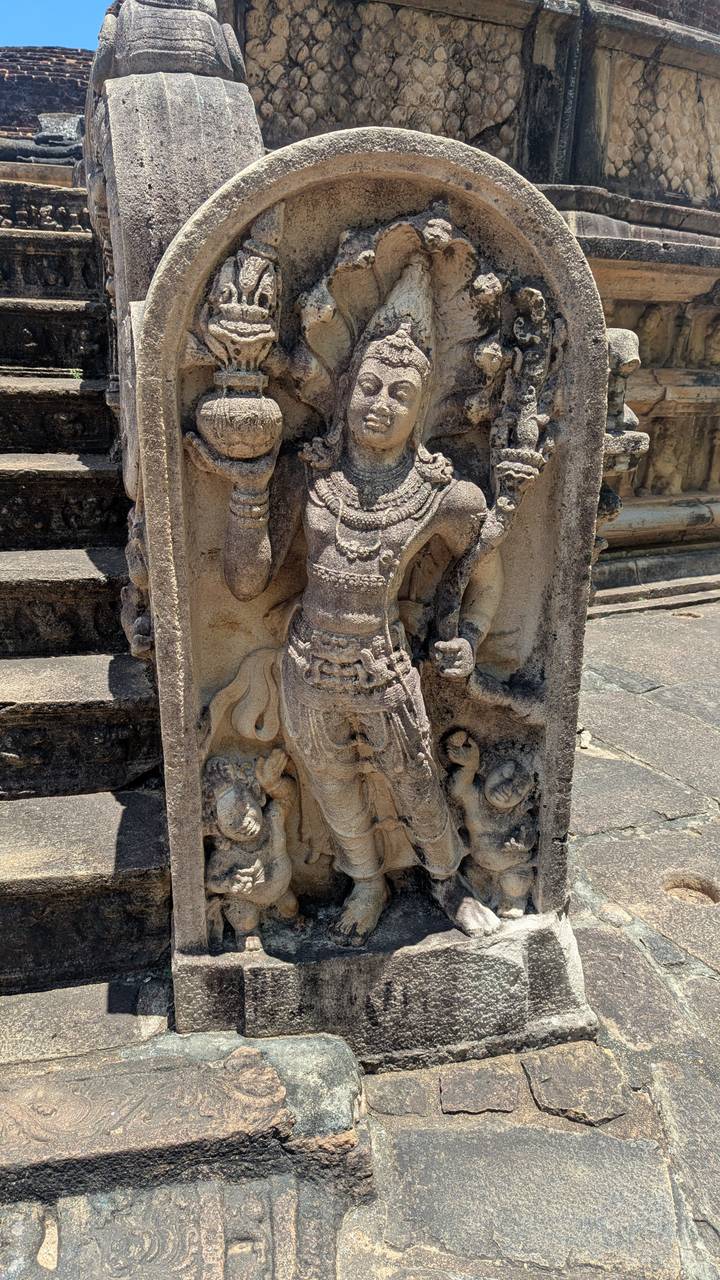 Close-up of an intricately carved guardian stone figure at an ancient Sri Lankan temple, lit by bright daylight.