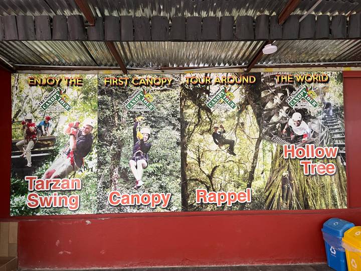 Advertising board with photos promoting canopy tours, tarzan swing and rappelling activities.