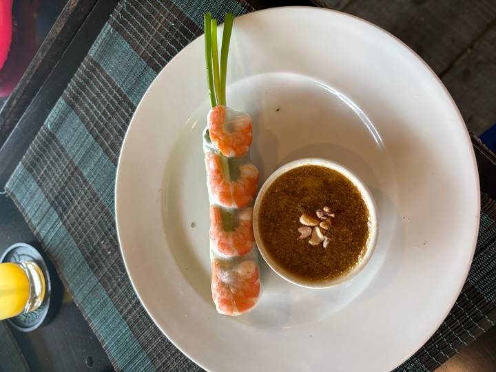 Fresh Vietnamese shrimp spring roll served with peanut dipping sauce on a white plate.