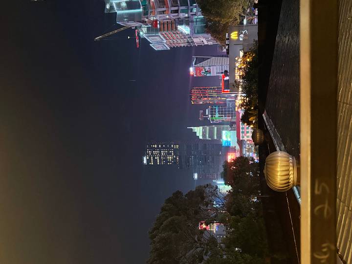 Night skyline of Ho Chi Minh City with colourful neon-lit skyscrapers against a dark sky.