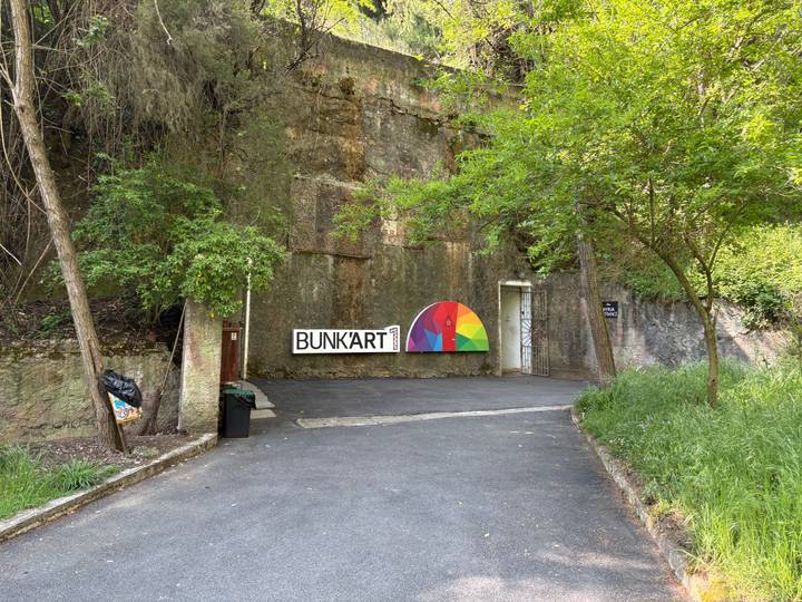 Entrance to Bunk’Art 1 museum built into a cliffside bunker, marked by a colourful semi-circular mural.