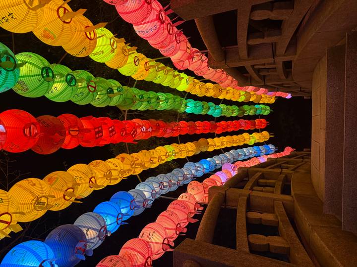 Vibrant rainbow lantern tunnel illuminated at night during a Korean festival.