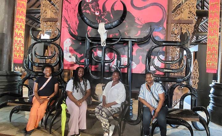 Visitors seated on ornate black horn-shaped chairs inside a dimly lit artistic hall.