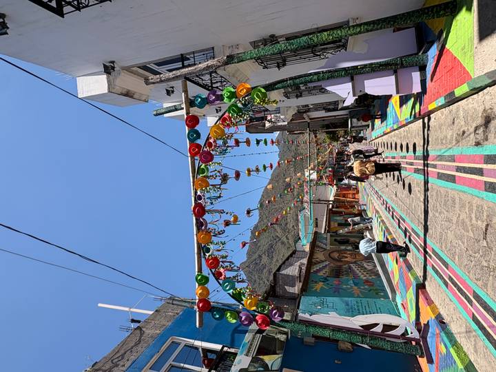 Colorful pedestrian street decorated with hanging pinwheels and painted pavement in a mountain town.