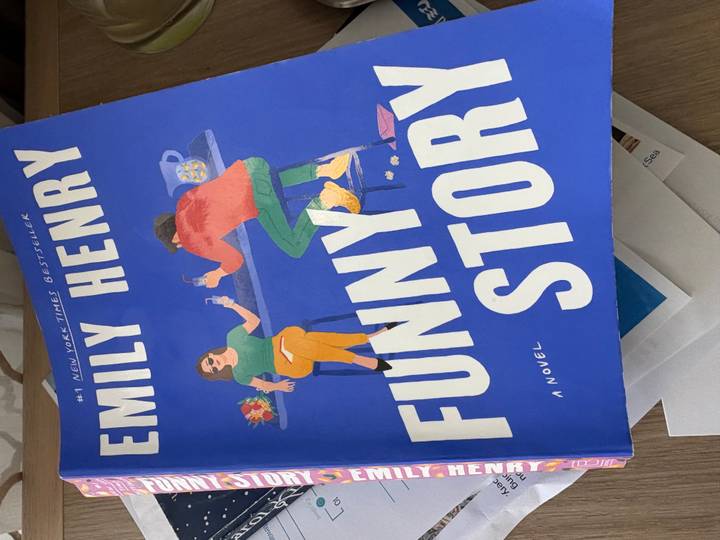 Close-up of the novel 'Funny Story' by Emily Henry resting on a table indoors.