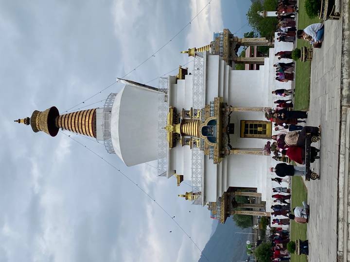 Large white chorten stupa with golden spire surrounded by worshippers circling the base in Bhutan.