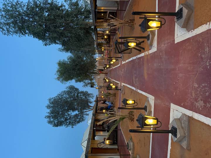 Neat pathway lined with lanterns between luxury desert camp tents at dusk.